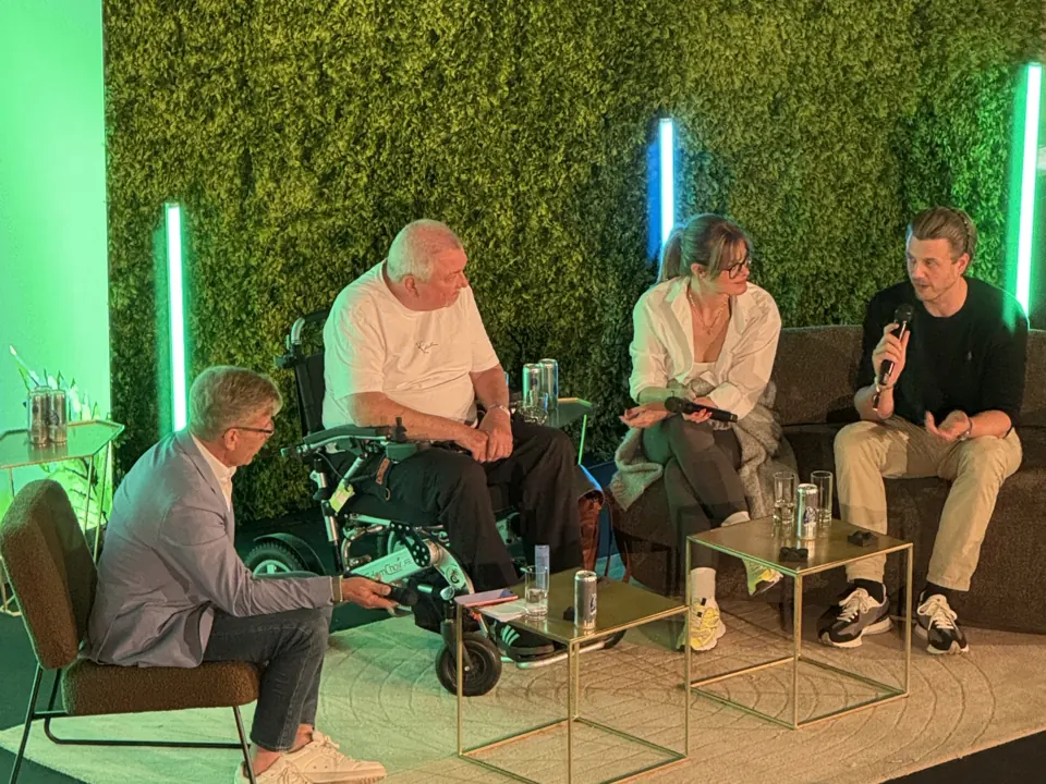Podiumsrunde mit vier Personen auf der Messebühne vor einer Pflanzenwand mit LED-Leuchtstäben.