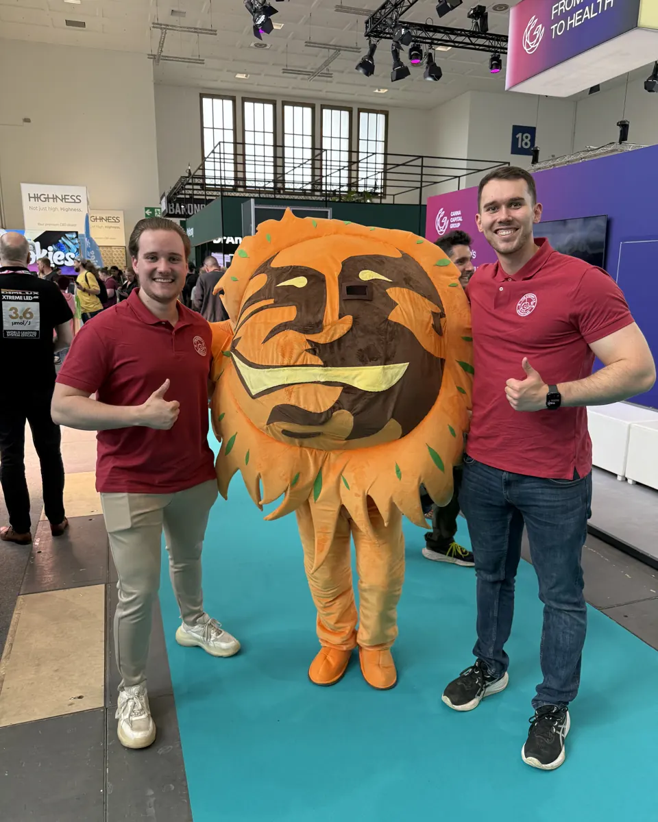 Chris links und Lars rechts neben dem Sonnenmaskottchen auf der Messe.